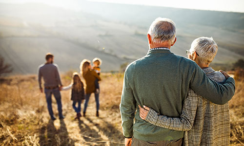 Senior couple watching a family of four walk down a mountain path in front of them